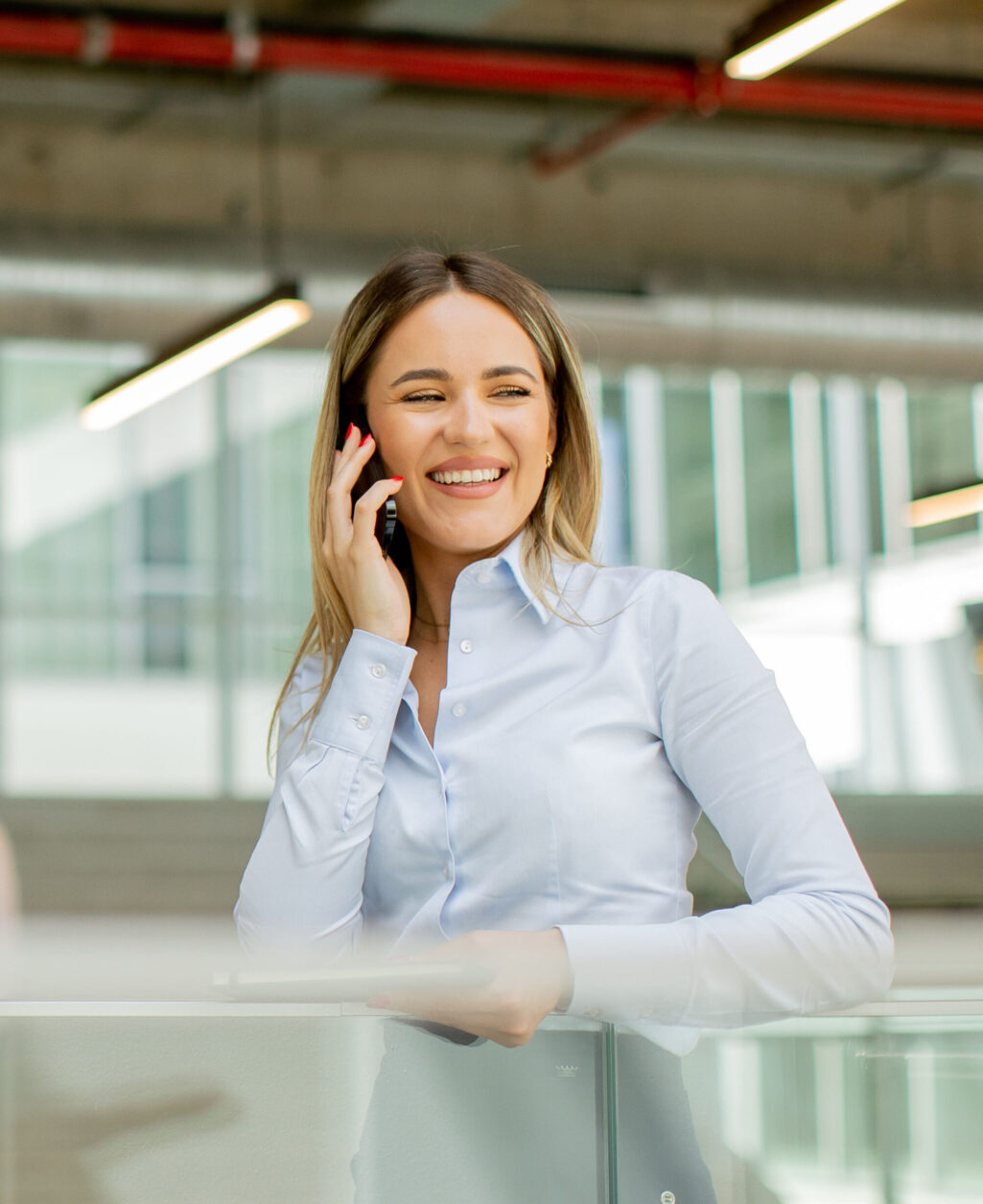 Young woman with notebook using mobile phone and standing in the